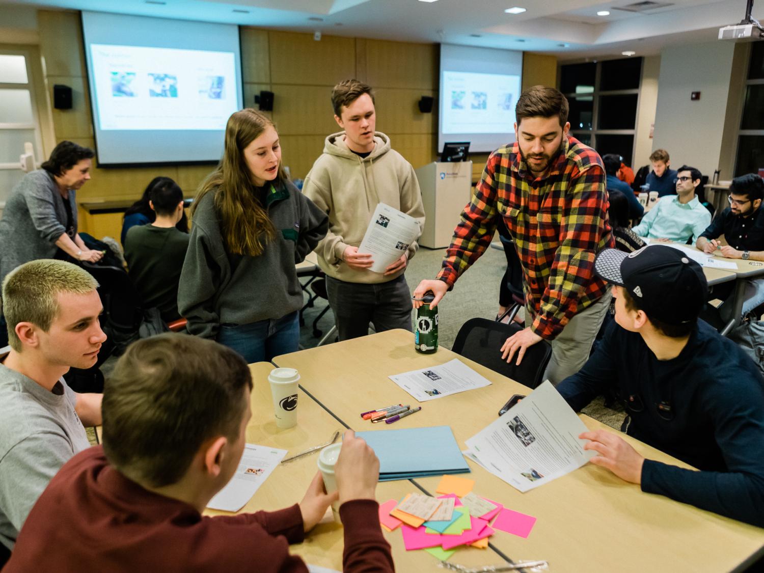 Students around a table interact with maker supplies