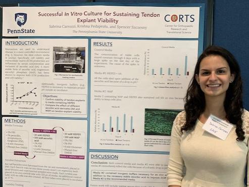 Woman smiling and posing with her research poster.