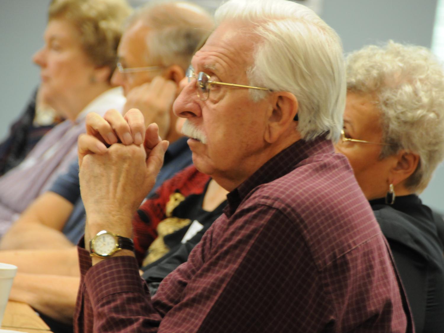 A group of older adults listen to a lecture.