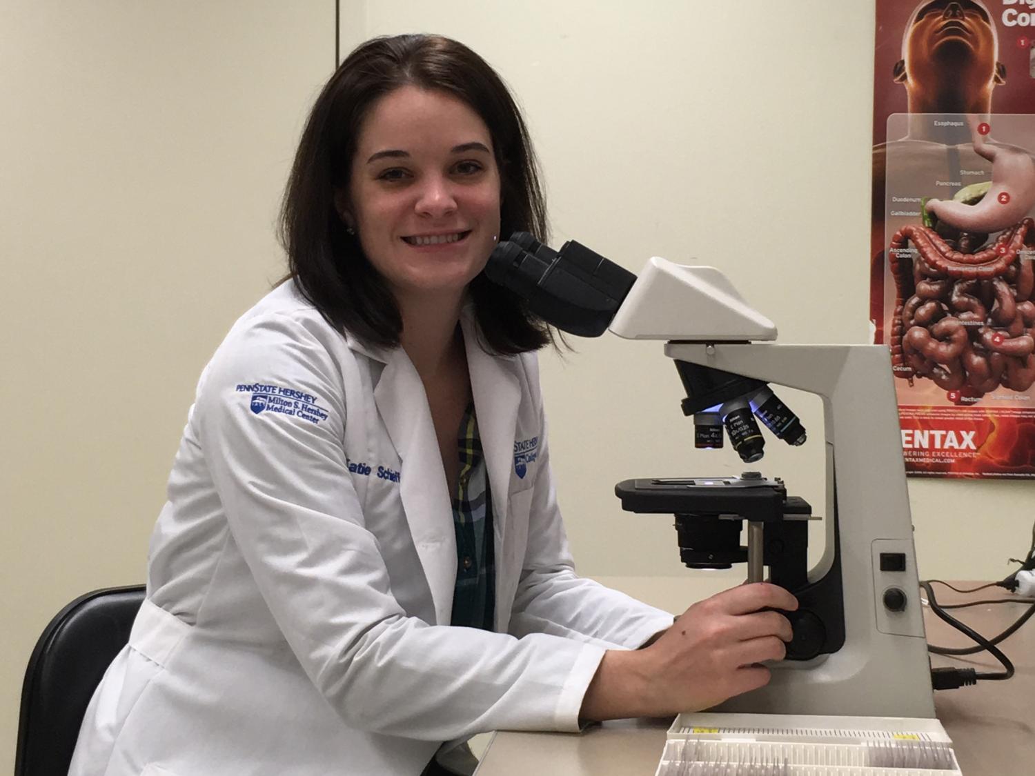 Image of Katie Schieffer with microscope in white lab coat