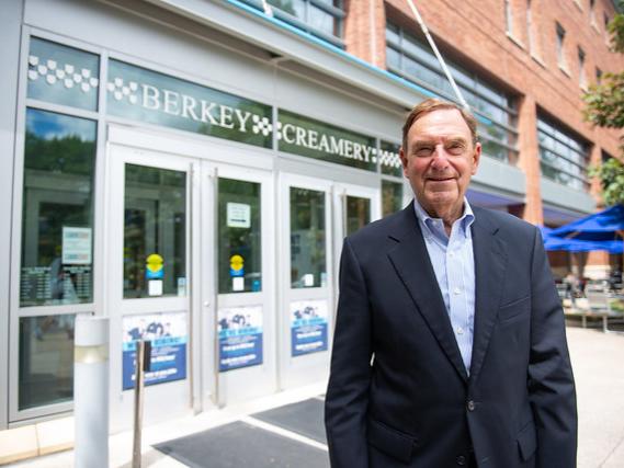 Man stands outside Berkey Creamery in blue shirt with suit jacket, smiling at the camera.