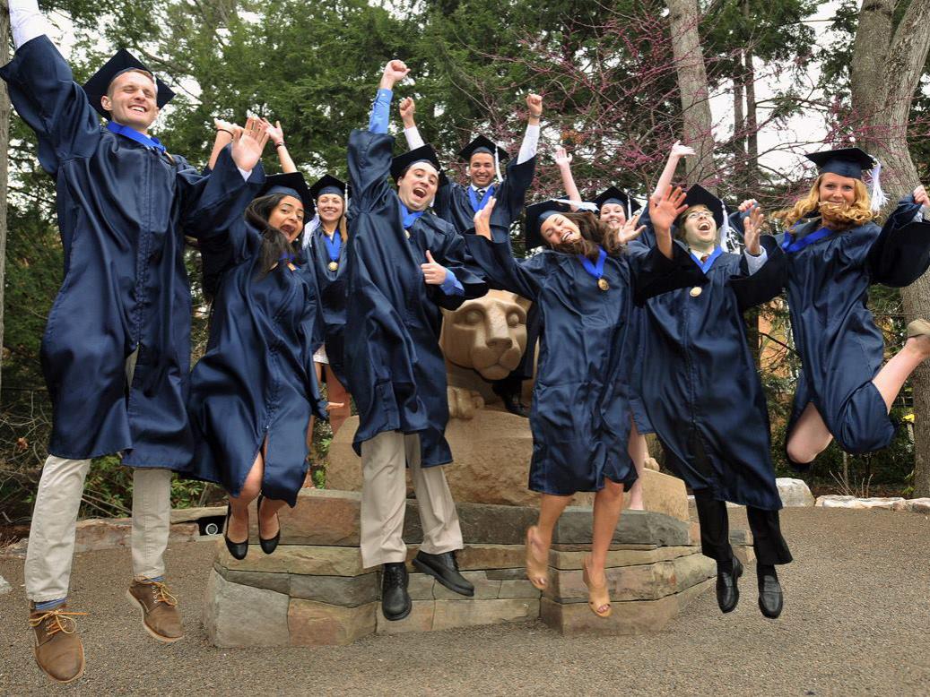 Honors students in gowns jumping in the air