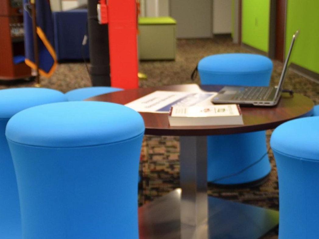 Blue stools surround a collaborative table at Fayette LaunchBox space