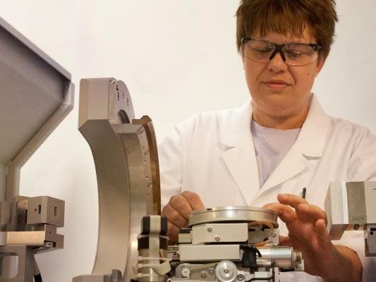 Woman in glasses and white lab coat working with a machine