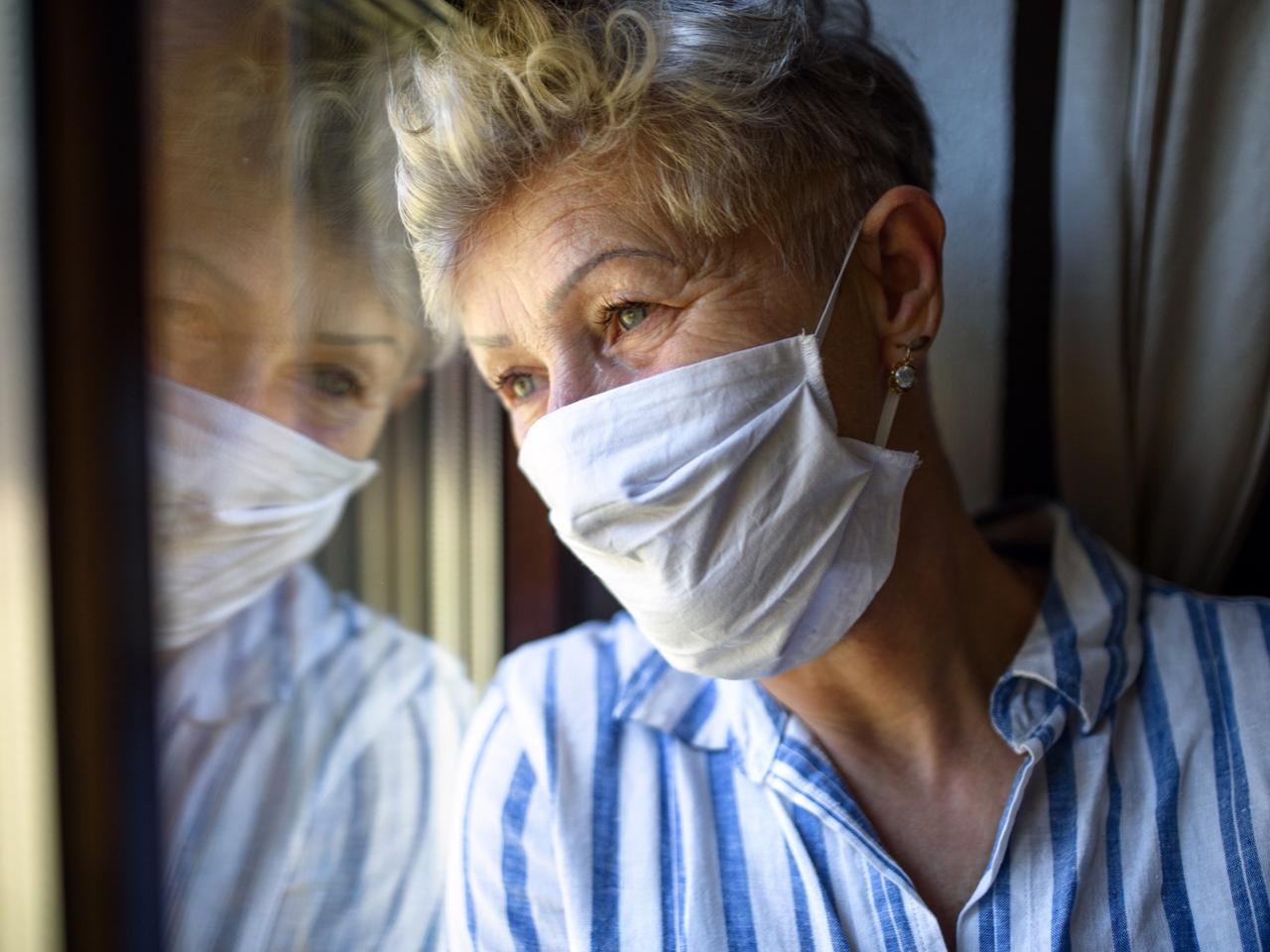 woman in mask looking out window