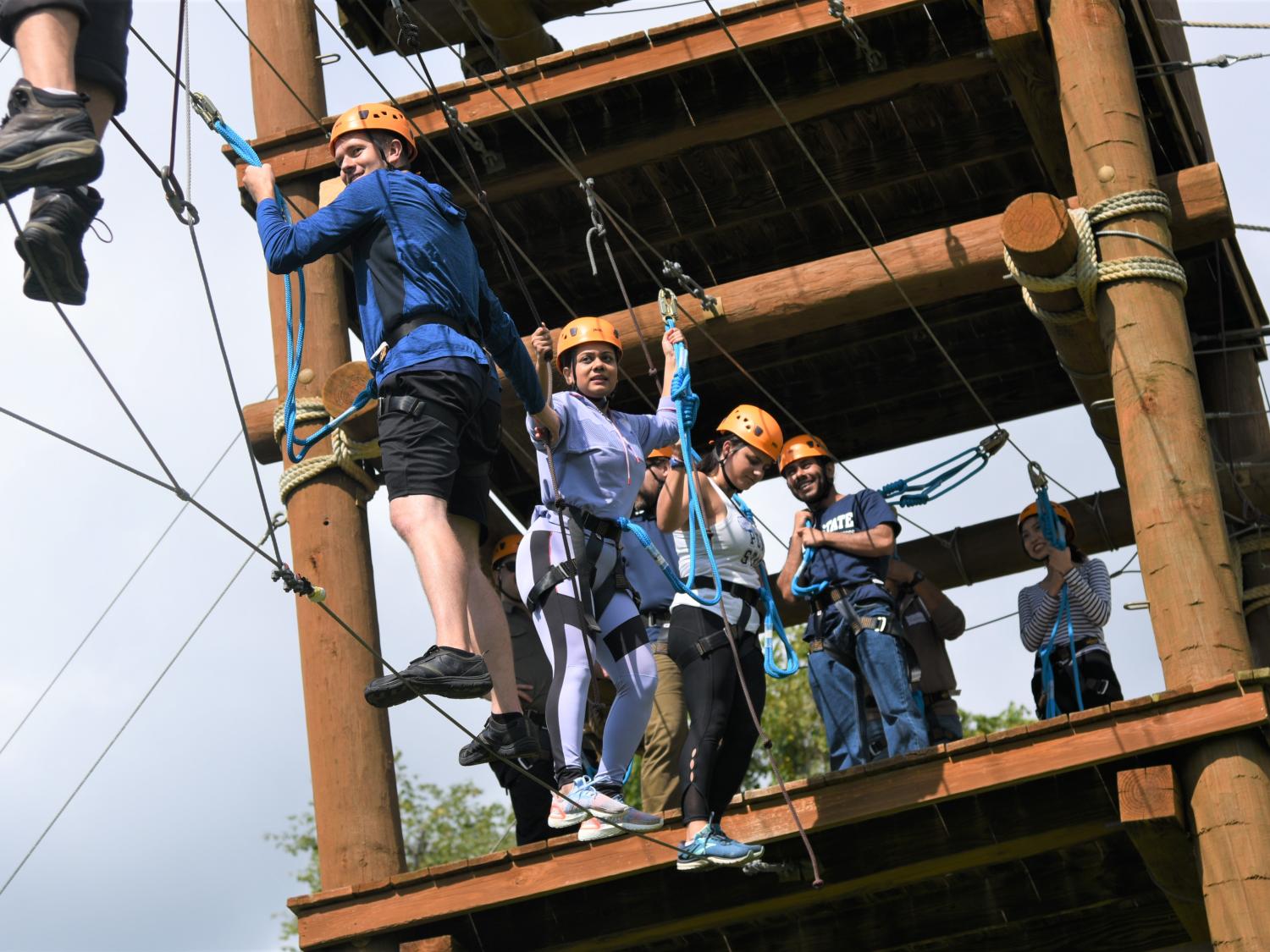 Penn State Smeal graduate students balancing on a high ropes course as part of a leadership immersion activity. 