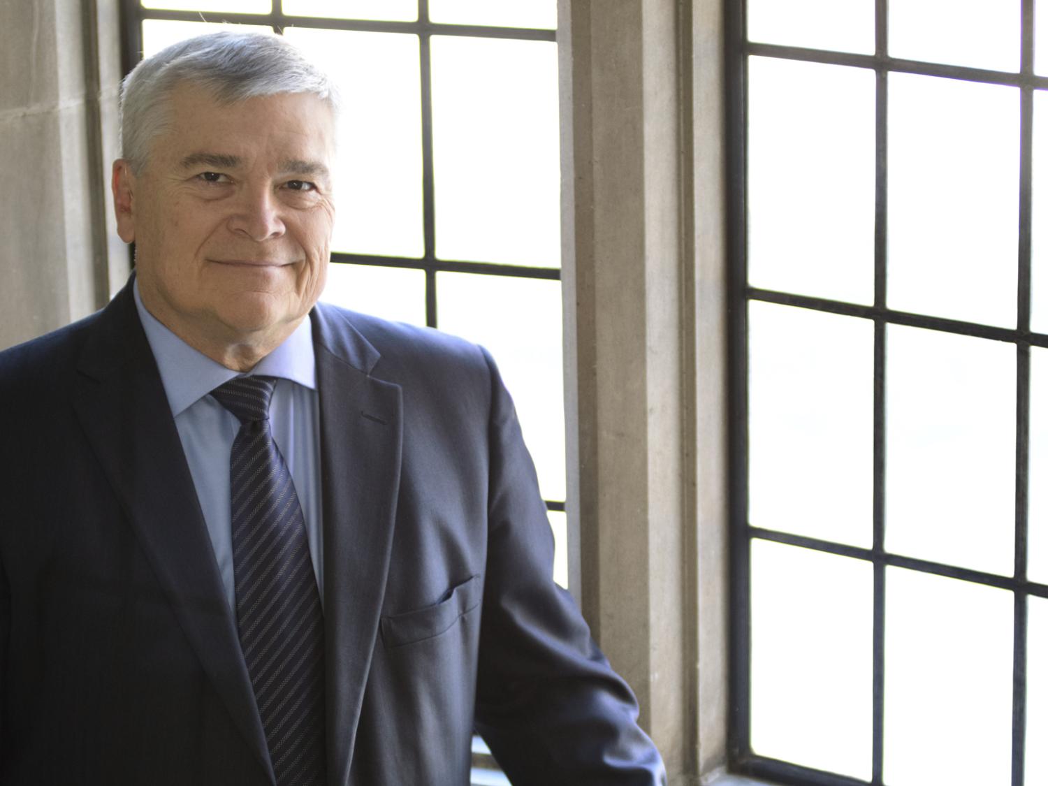 Dr. Eric Barron stands in front of a window at the Schreyer House on Penn State's University Park campus.
