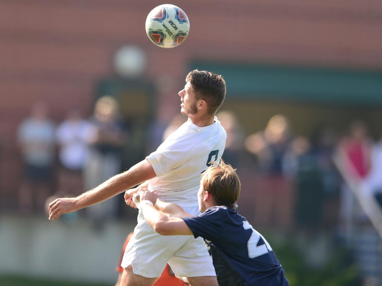 A Penn State Behrend soccer player heads the ball during a game.
