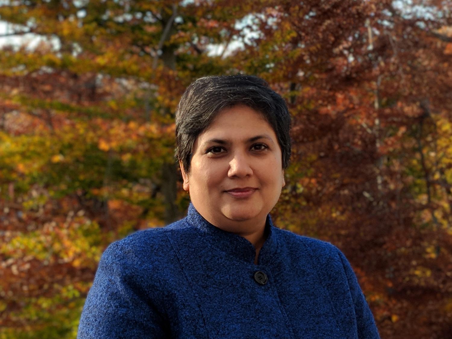 Sonali Dalal in front of a tree with orange and red leaves