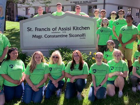 student volunteers at local soup kitchen pose for a photo in front of the facility