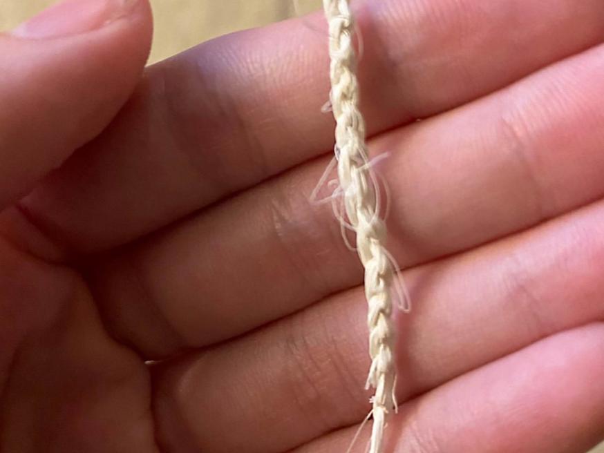 A white chain of fiber rests in the palm of a hand. 