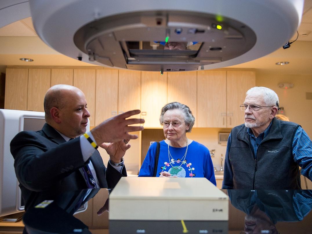 Three people talk next to a large medical machine