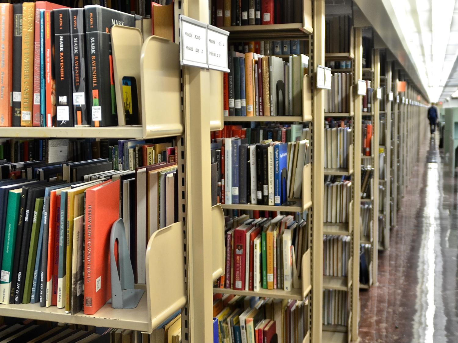 view of long walkway on right side with rows of bookshelves on left side