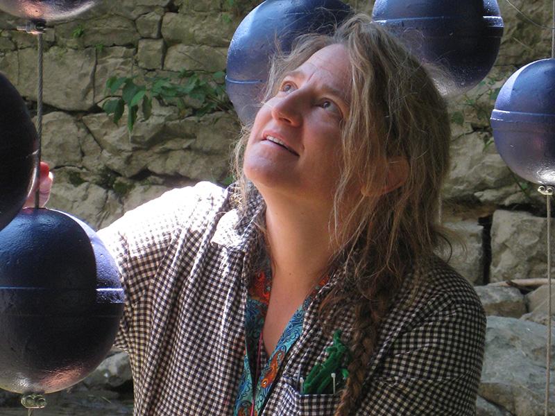The artist is pictured standing amidst one of her creations, which is made up of suspended dark orbs.