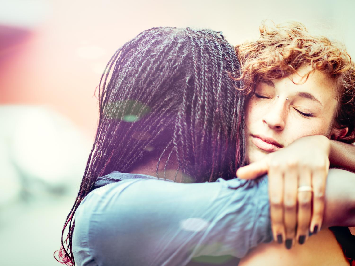 A Black woman hugs and supports a white woman