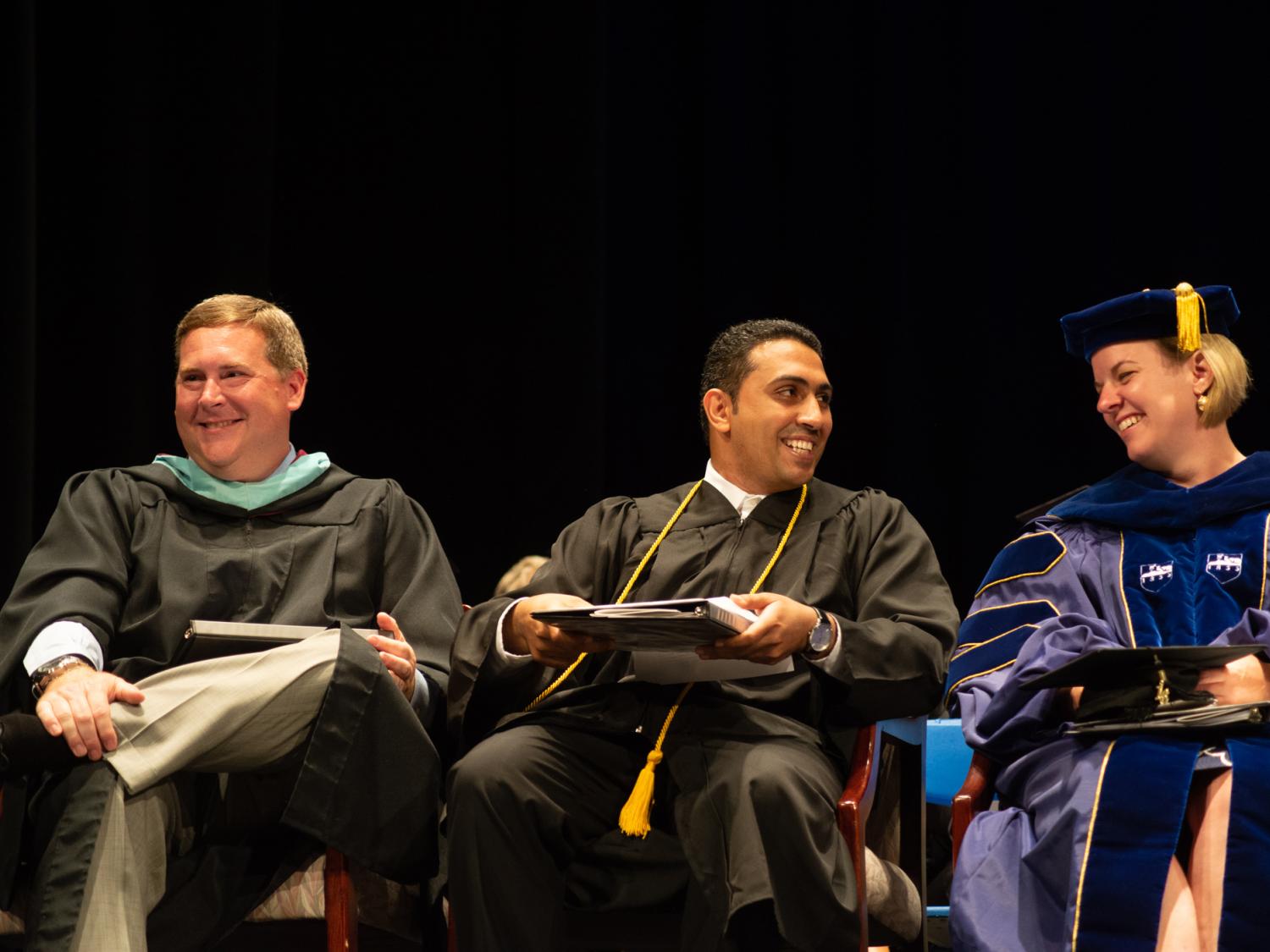 Three people in academic robes at a commencement ceremony