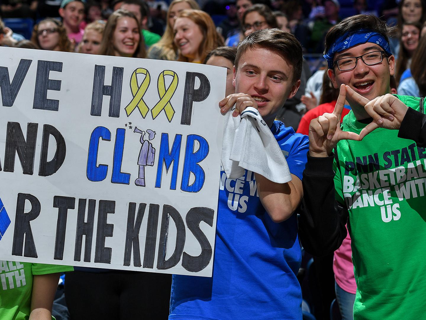 students holding a sign and cheering at a basketball game