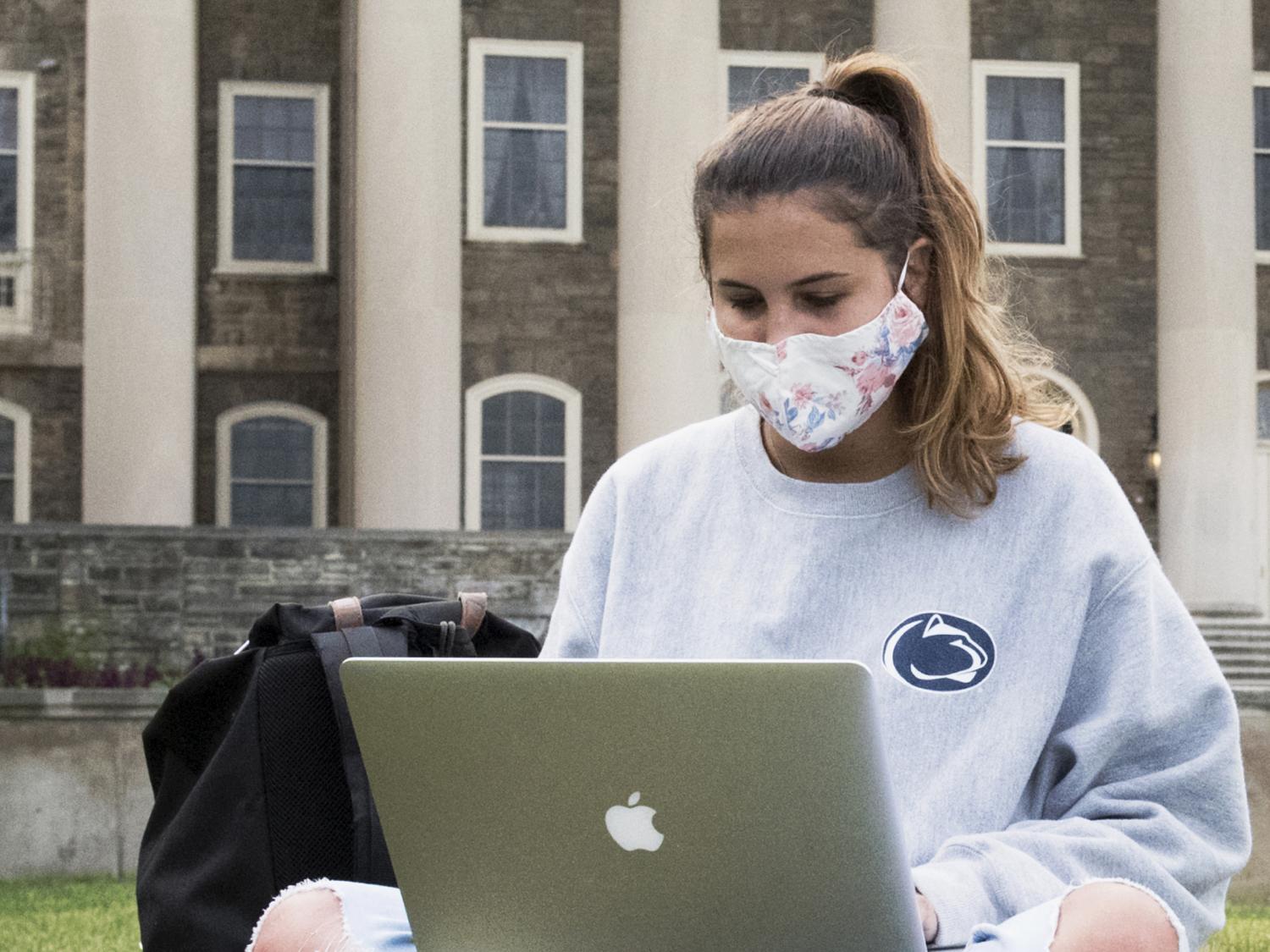 A student wearing a face mask on Old Main lawn. 