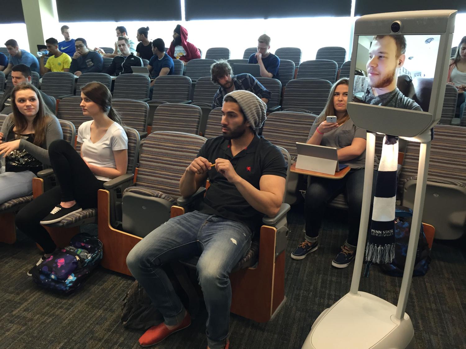 Student sits next to peers via the Beam as they listen to instructor.
