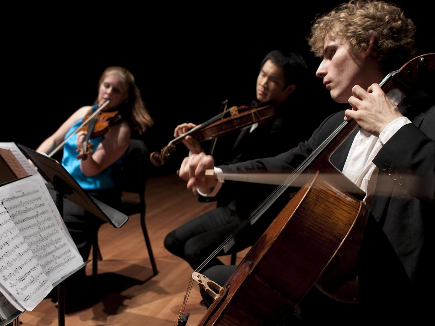Three students performing music onstage