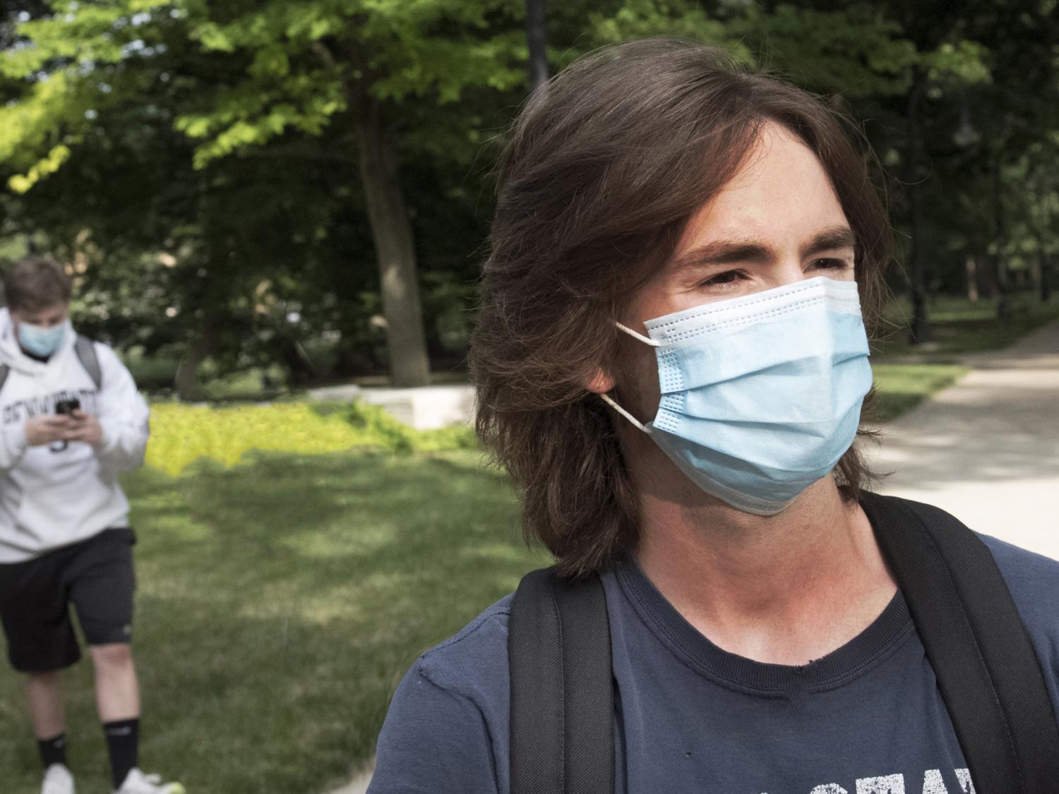 Two students wear walk across campus at University Park wearing face masks.