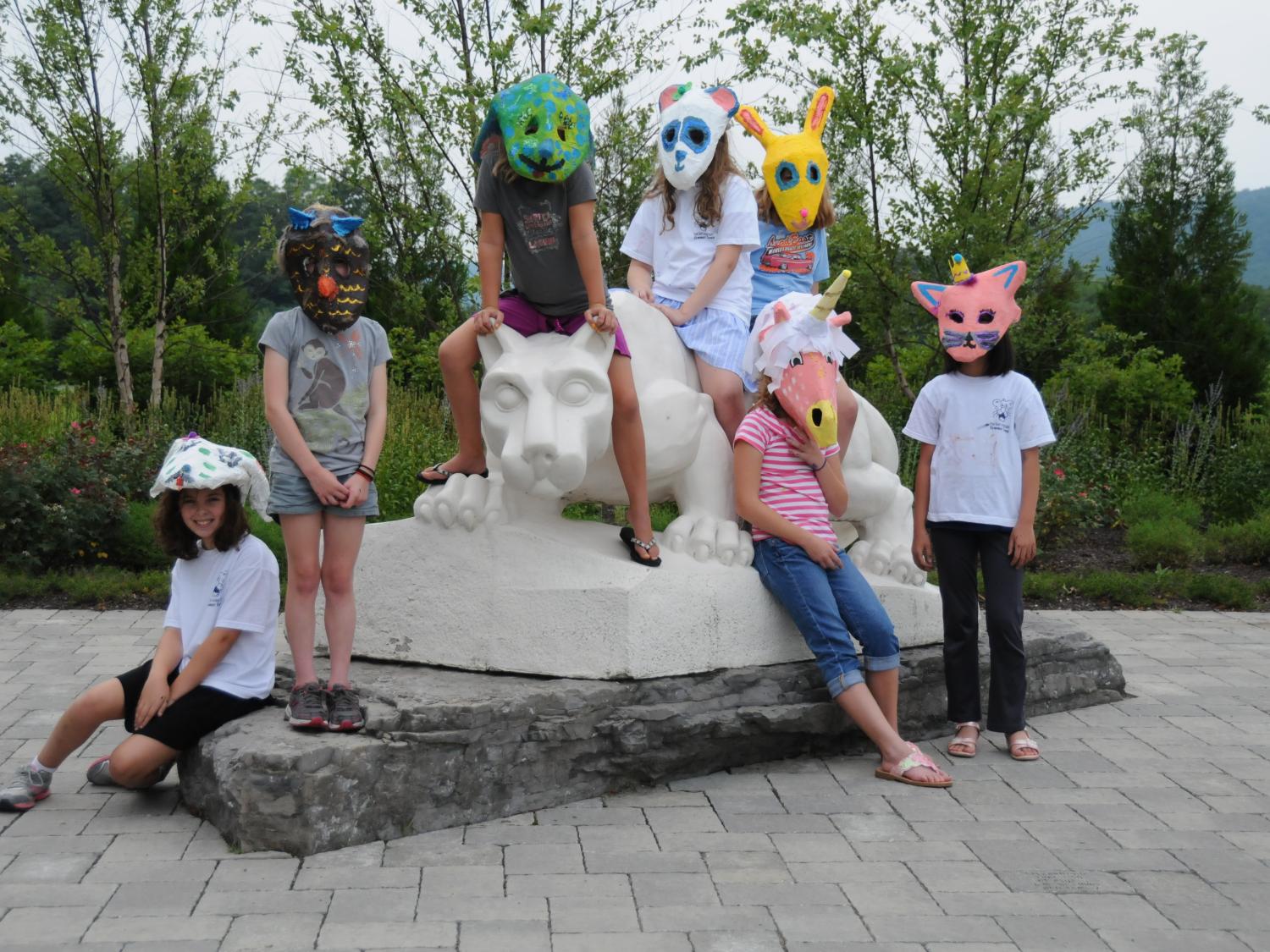 Youth campers gather around the Nittany Lion in their artistic masks.