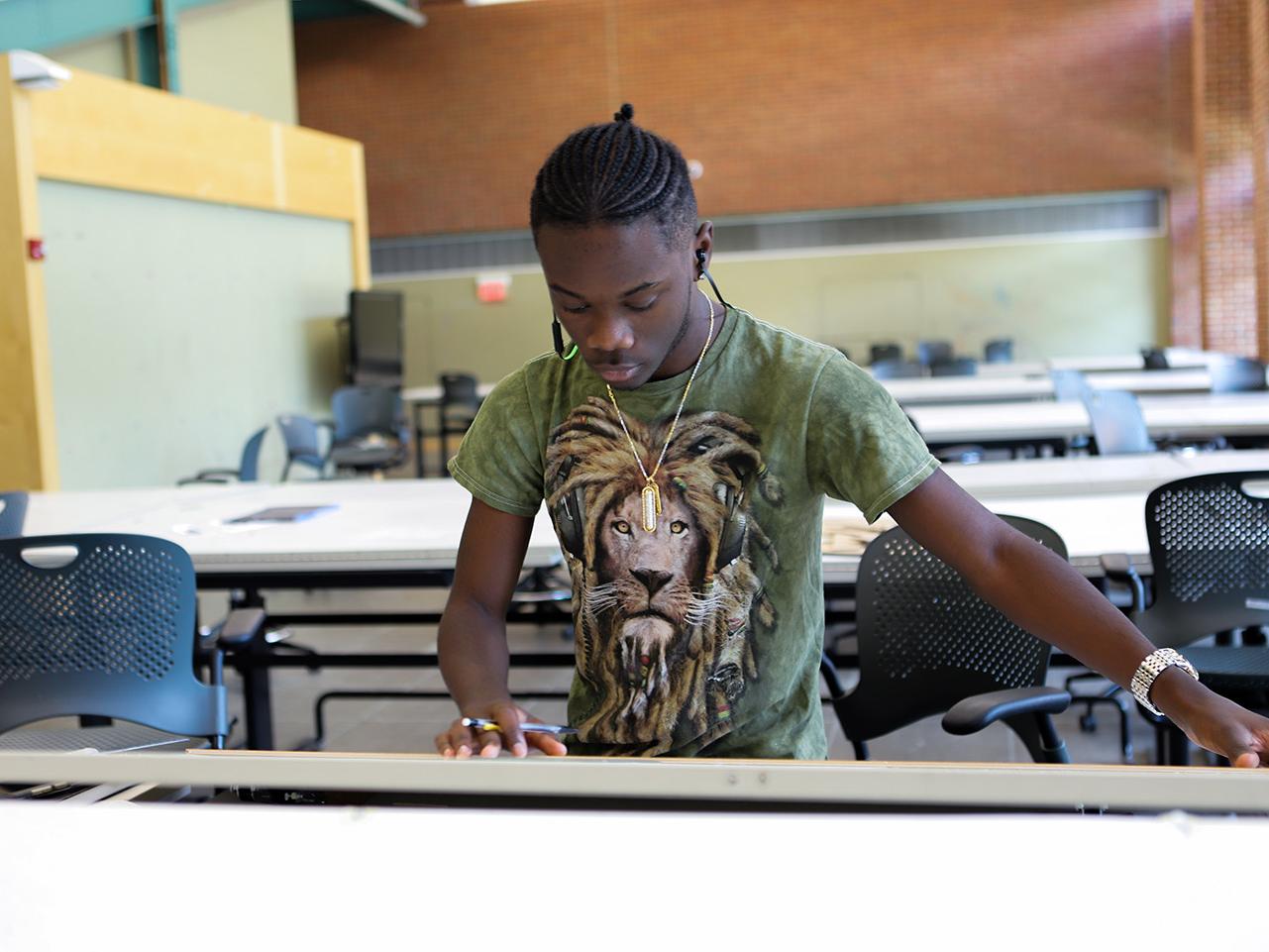 A high school student works on a sketch at a drafting table.