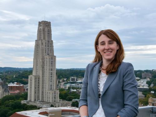 Woman posing on rooftop with city behind her. 
