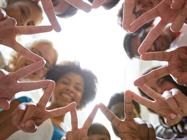 A circle of people giving the peace sign