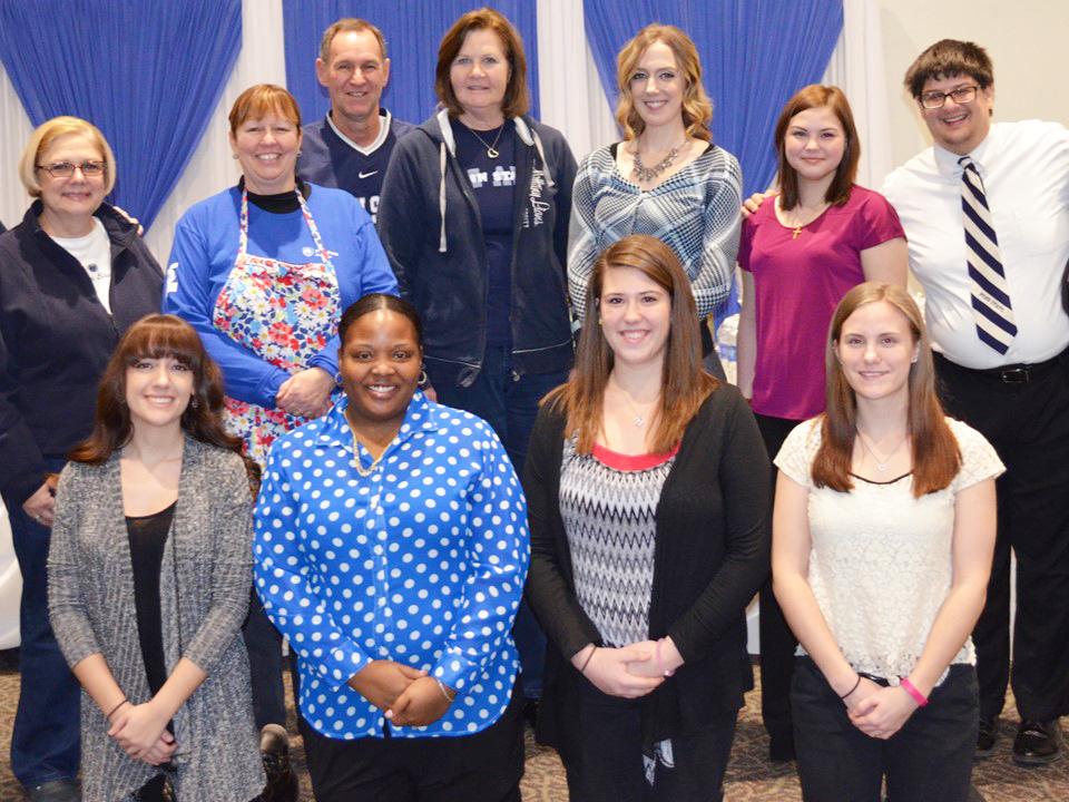 A group of people stand and kneel for a picture in the campus' auditorium before the 2016 Spaghetti Dinner