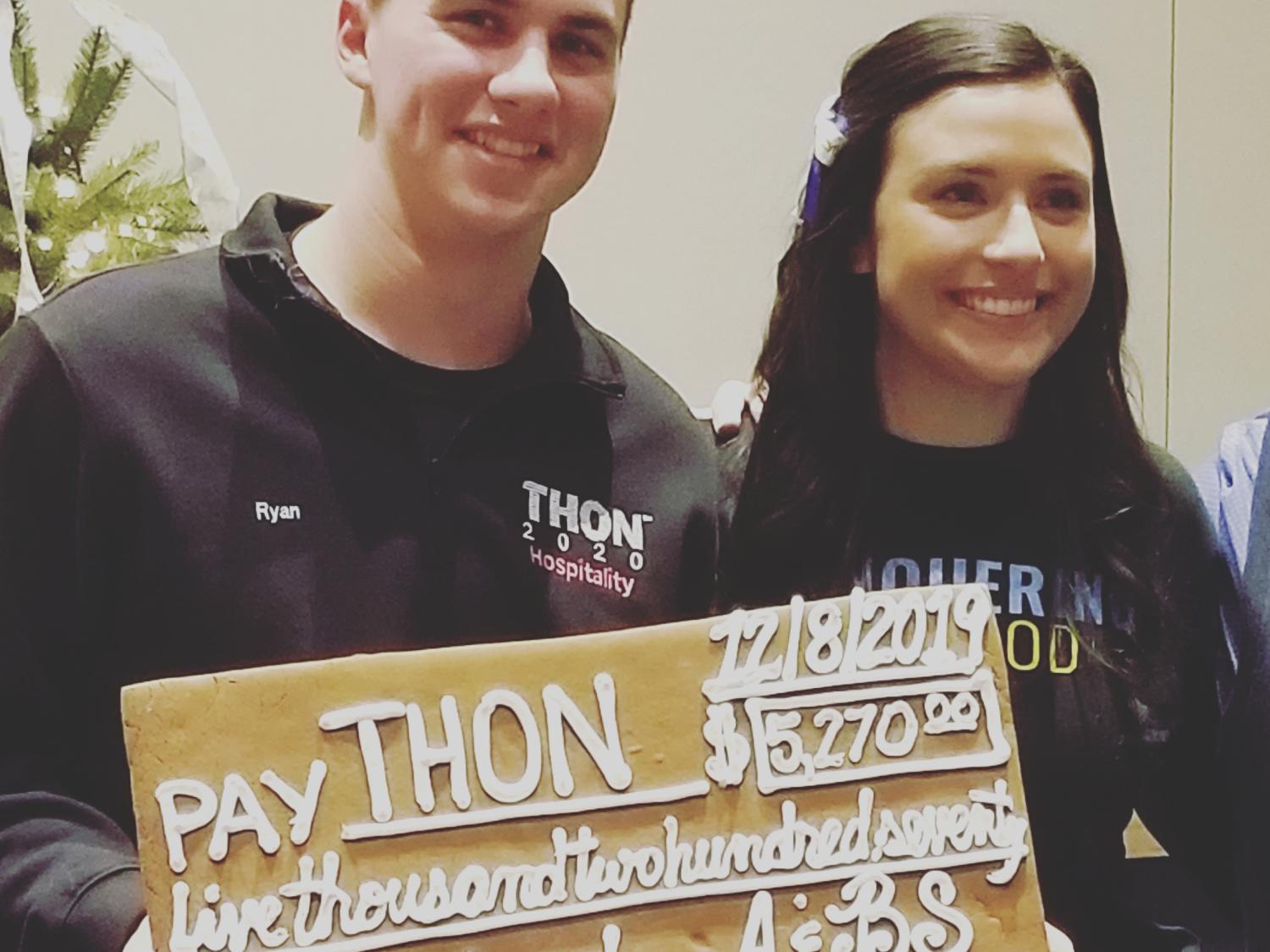 Two students hold gingerbread check for $5,270