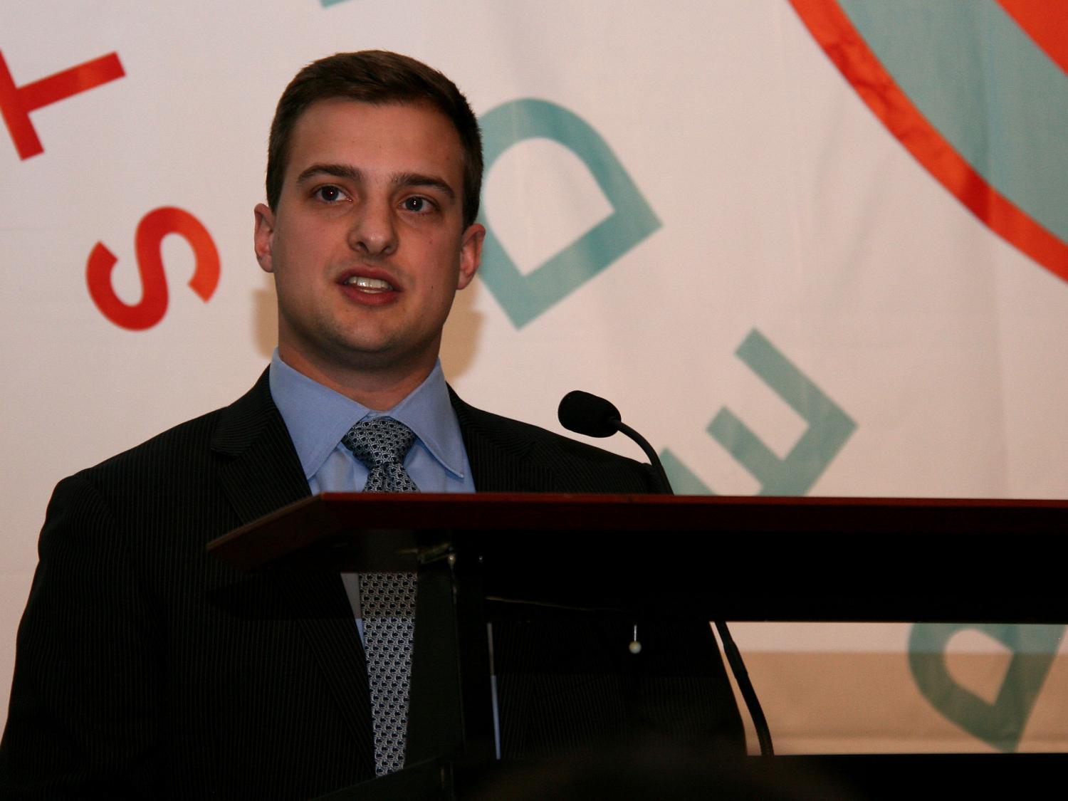 male Penn State student addresses crowd behind speaker's podium