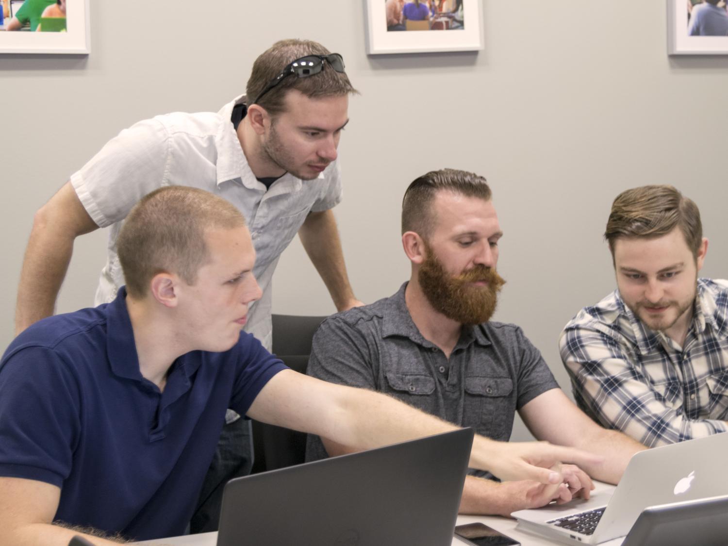 Four members of the Competitive Cyber Security Organization gather around a computer