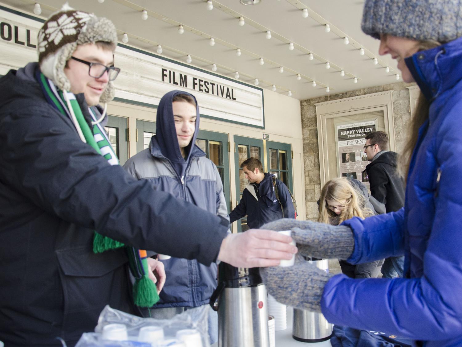 Two students giving out hot cocoa