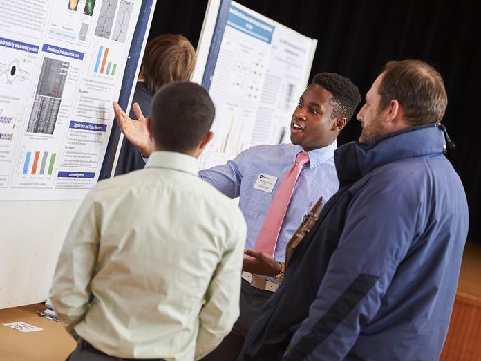 Student Thomas Derby presents his research poster to volunteer judges at the 2016 Undergraduate Exhibition.