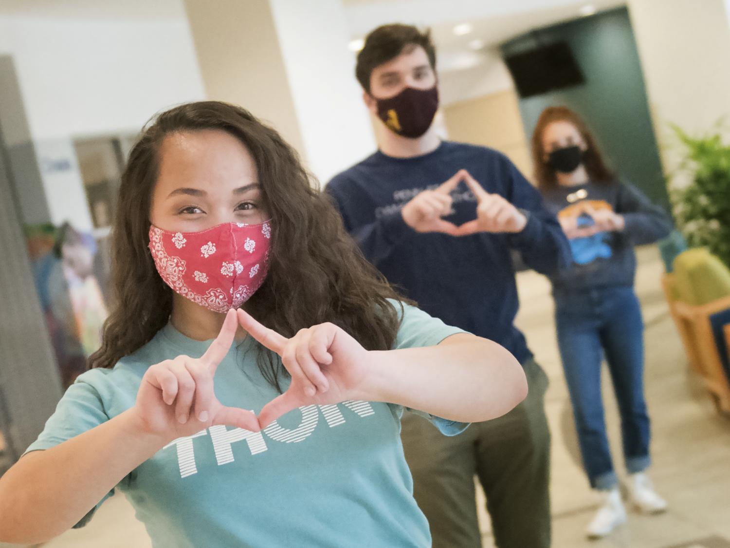 Penn State students Jasmine Forsberg, Andy Mader and Addison Albert, each wearing masks and maintaining physical distance, hold up their fingers to resemble the Four Diamonds icon.
