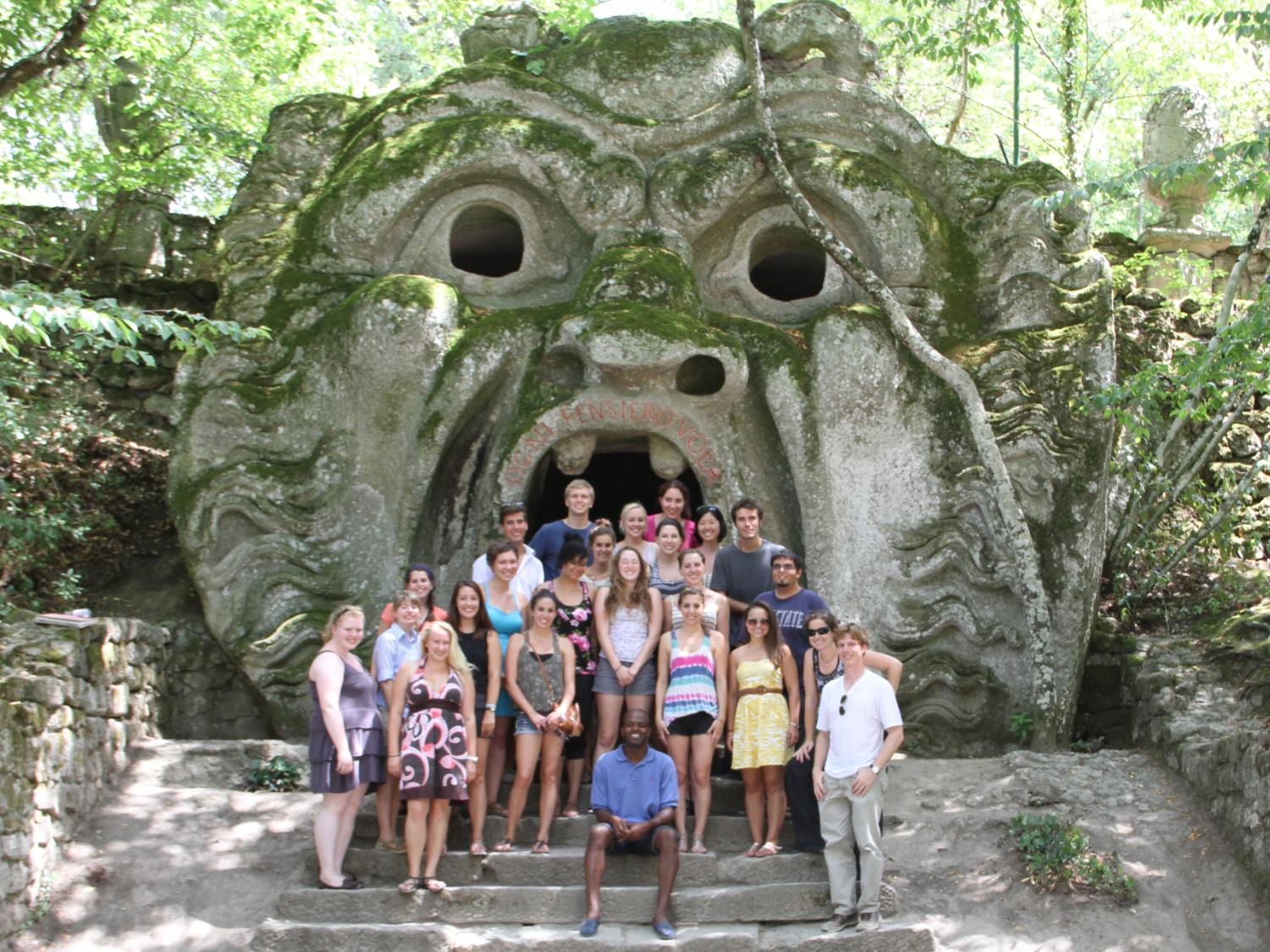 A group of students standing in front of Italian ruins.