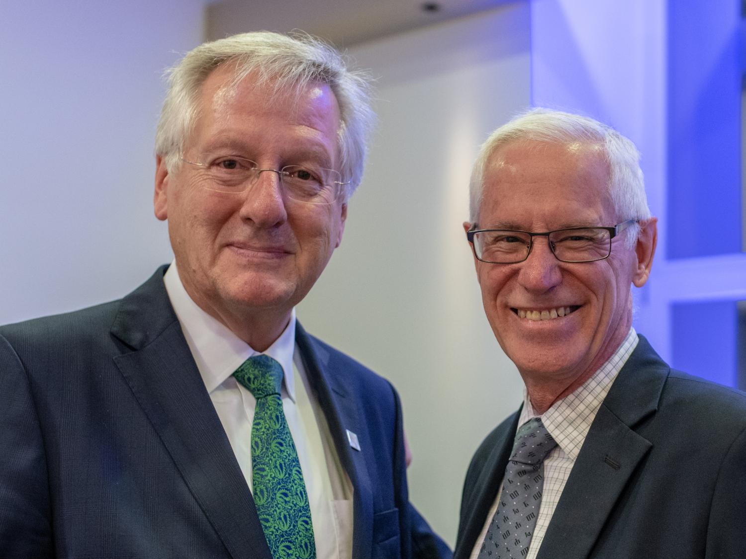 Two men in suits are pictured facing the camera.