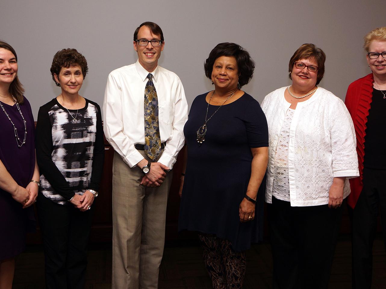 group of five women and one man standing in a row after being honored at a ceremony