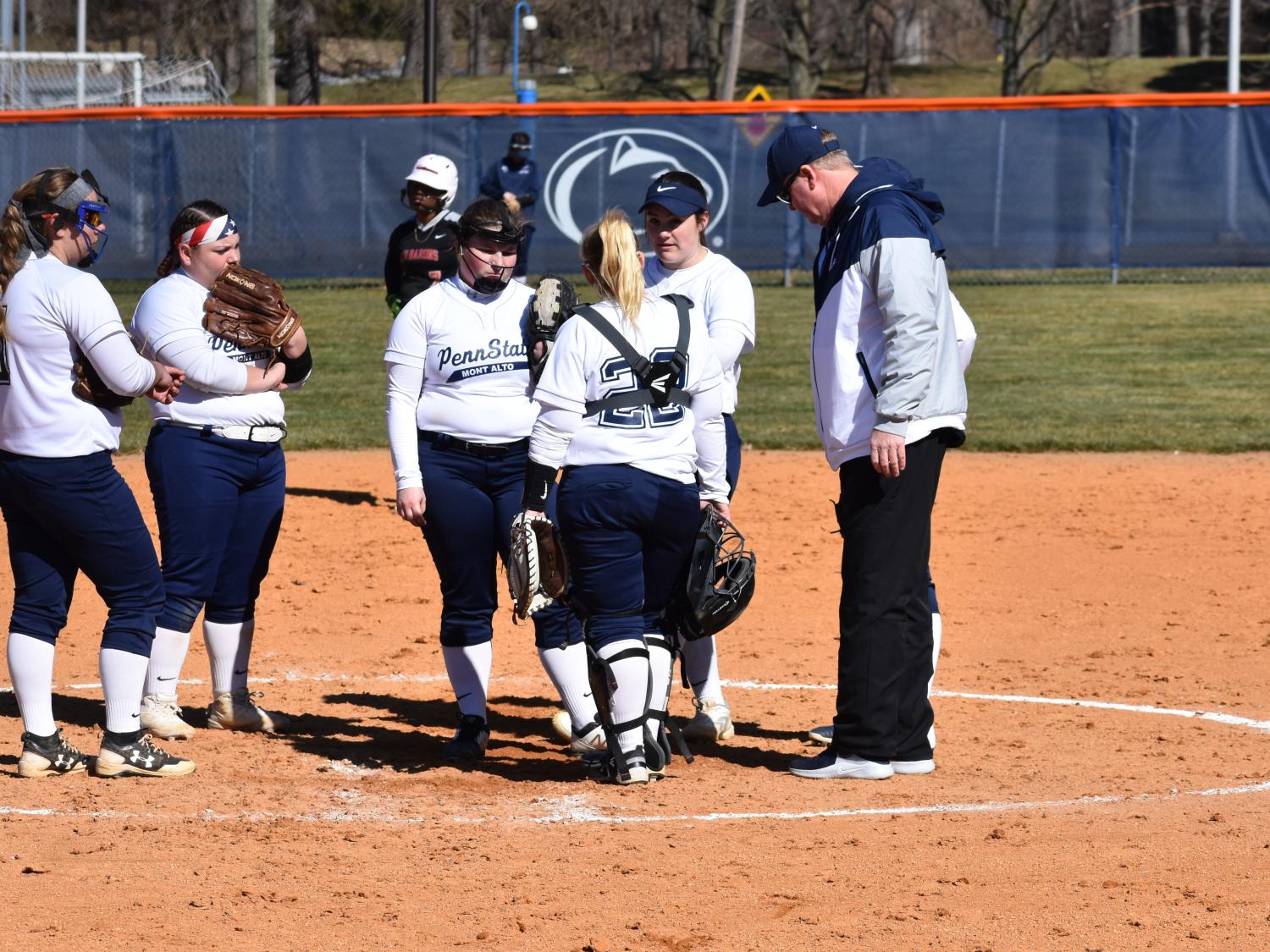 Women's softball players convene on the mound