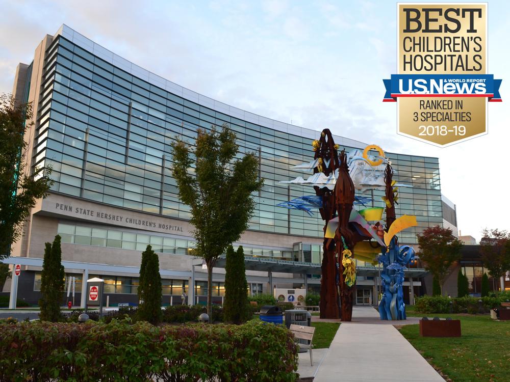A view of the front of the Penn State Children's Hospital building. A gold and blue badge reading "Best Children's Hospitals/U.S. News/Ranked in three specialties, 2018-2019.”