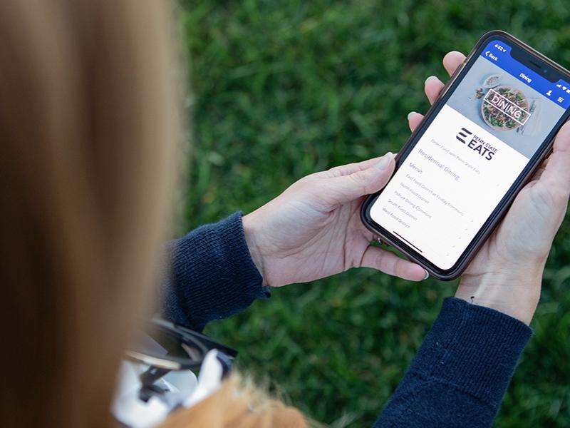 A female student uses the Penn State Dining app on her smartphone