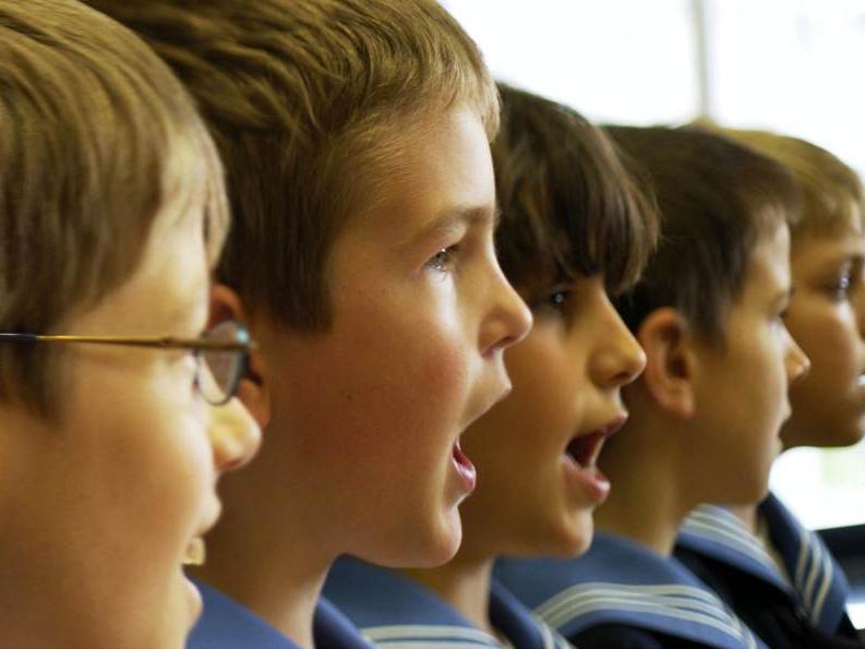 Five members of Vienna Boys Choir face right while they sing a hymn.