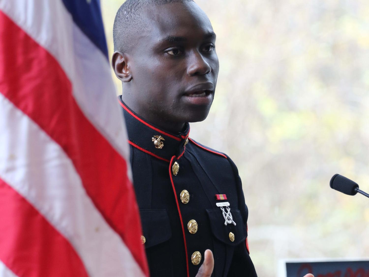 Veteran speaking and standing next to american flag