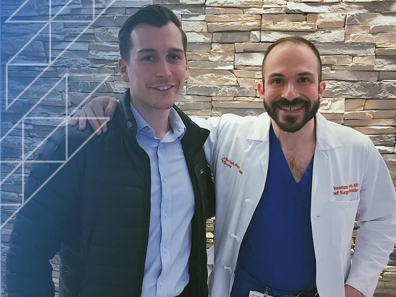 two men pose with arm around each other