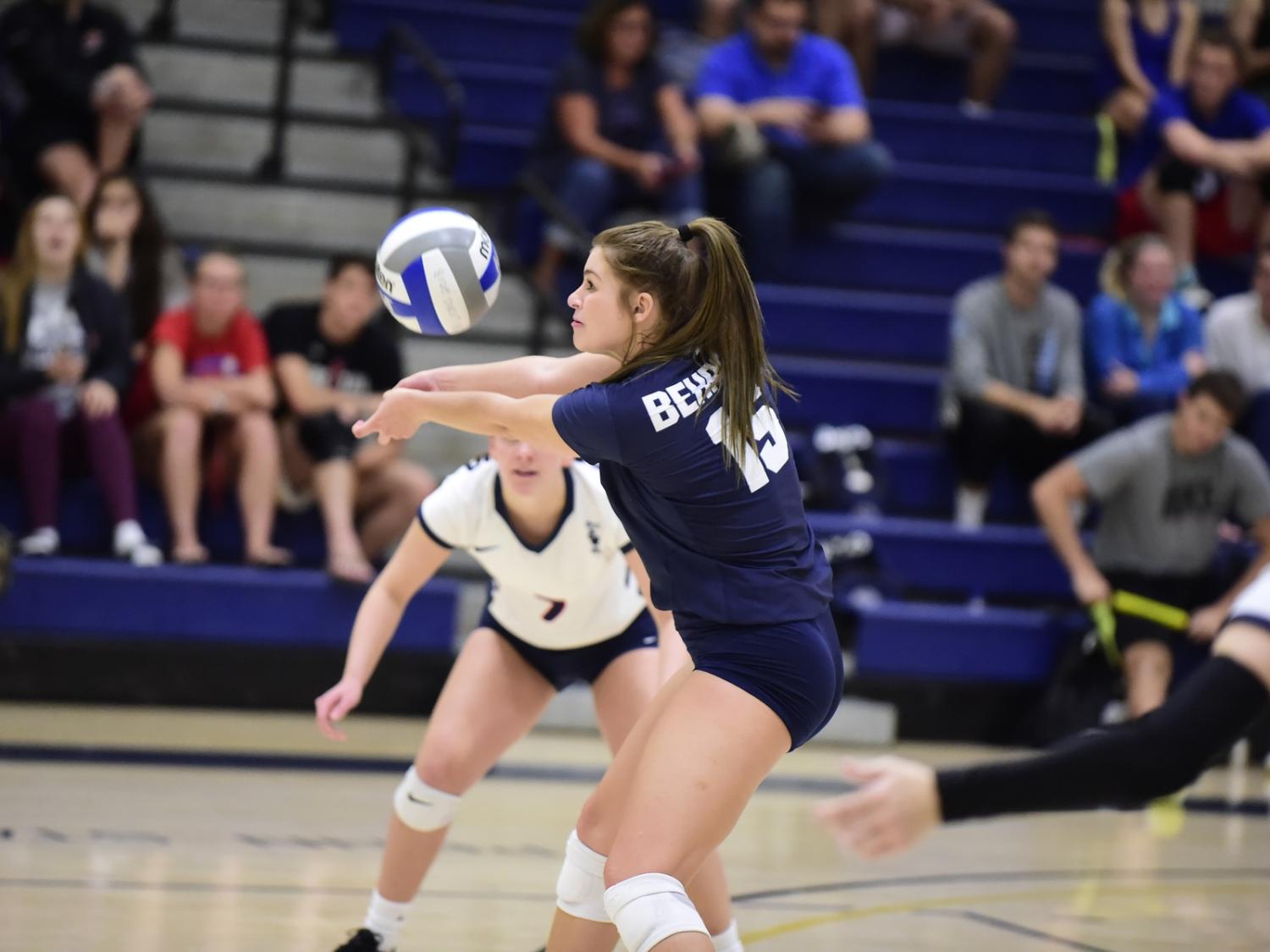 A Penn State Behrend volleyball player digs the ball during a match.
