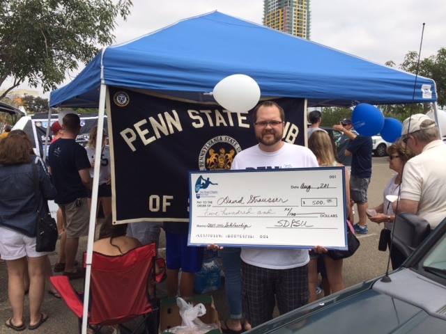 Student holding giant check in front of tent