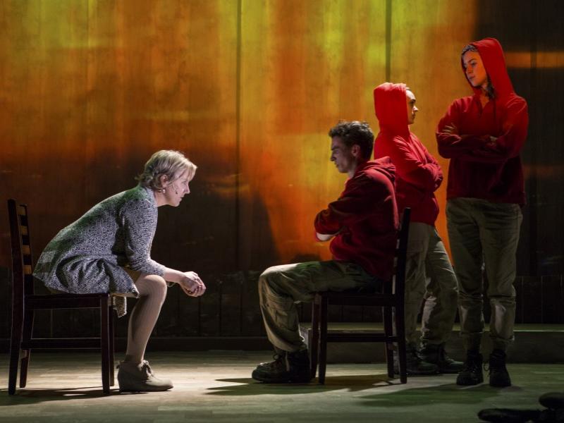 An actress portraying a parent sits in a chair and leans toward to an actor portraying her son in a scene from “Wilderness.”
