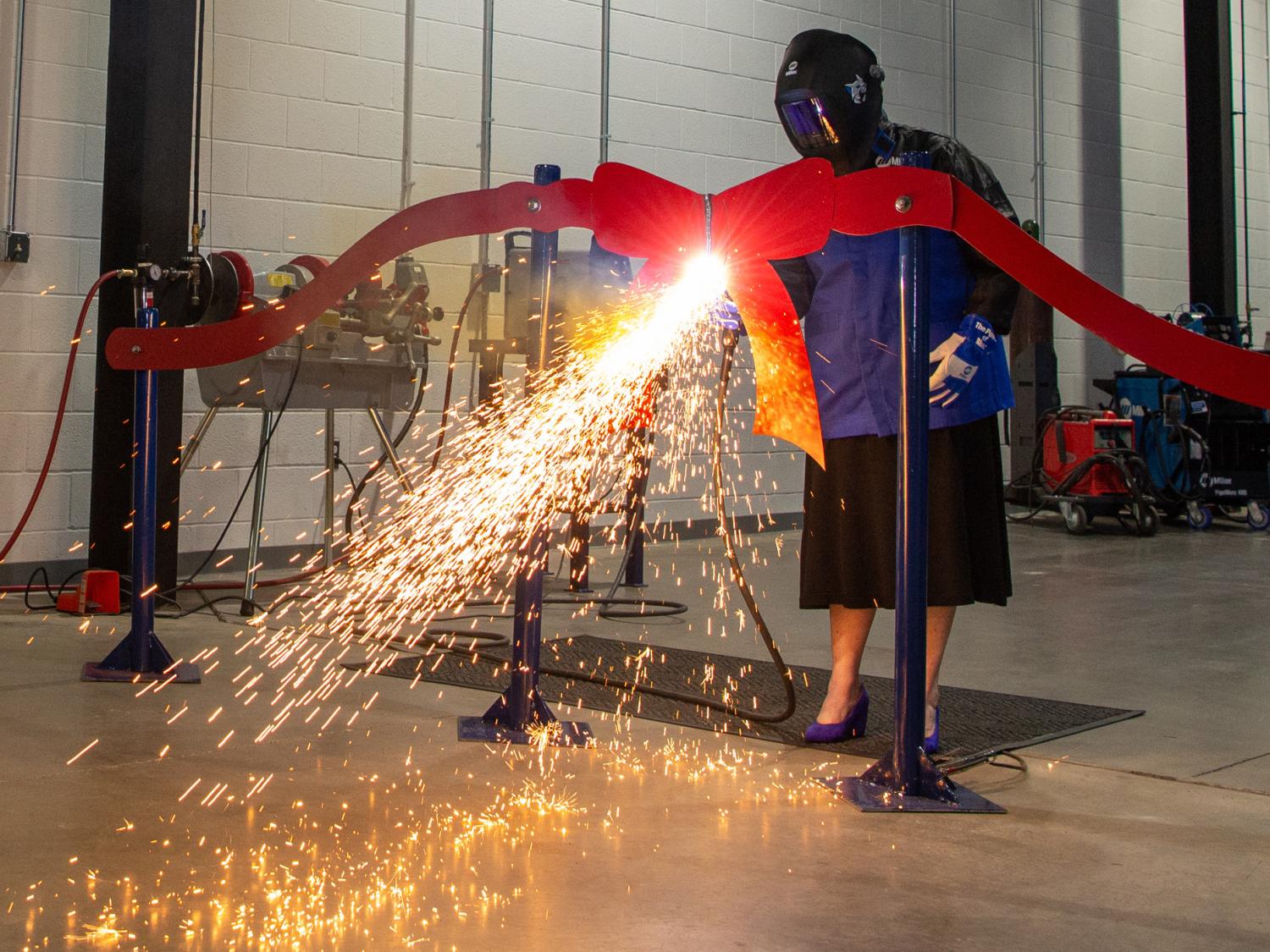 A man uses a plasma cutter to cut a metal ribbon