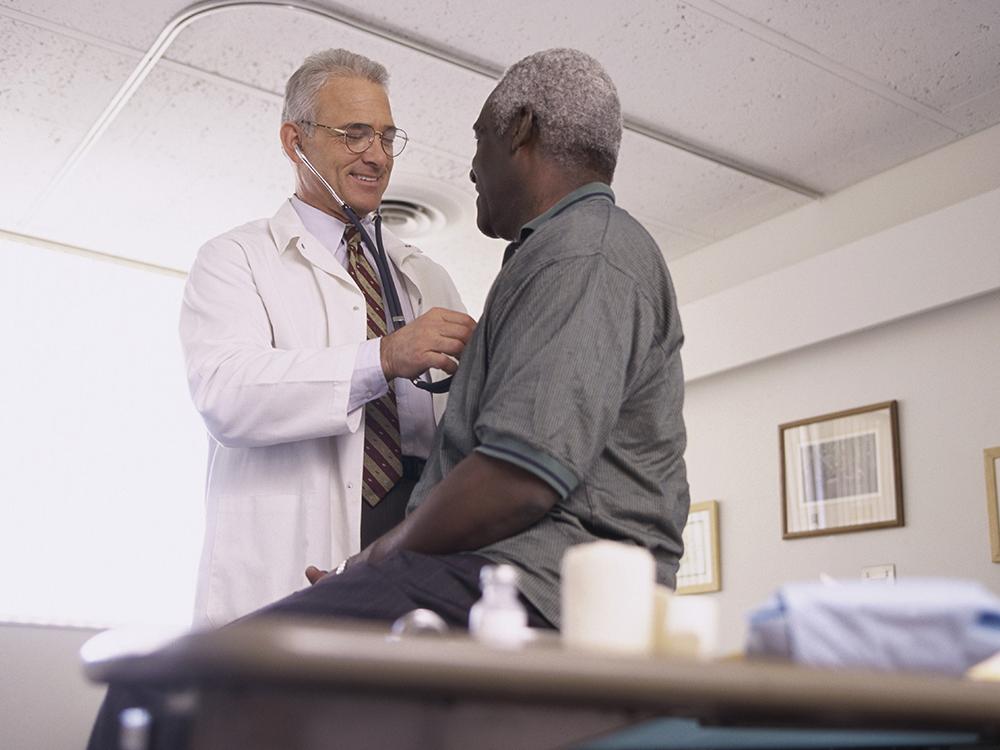 A male doctor examines a male patient.